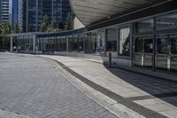 a person sitting at the bench in front of a mall that is empty of people