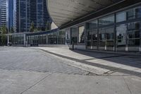 a person sitting at the bench in front of a mall that is empty of people