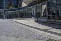 a person sitting at the bench in front of a mall that is empty of people