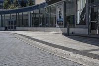 a person sitting at the bench in front of a mall that is empty of people