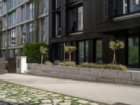 a person is riding down the sidewalk next to some green trees and bushes and a building