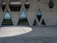 a concrete building with a lot of windows sitting on top of it with a circular pattern on the side