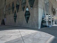 a view from the outside of an abstract, concrete building with lots of windows and glass on both sides