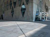 a view from the outside of an abstract, concrete building with lots of windows and glass on both sides