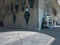 a view from the outside of an abstract, concrete building with lots of windows and glass on both sides