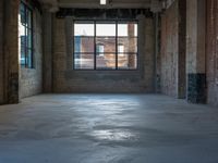 a empty industrial building with huge windows and a few windows in it, as seen through a dirty concrete floor