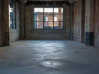 a empty industrial building with huge windows and a few windows in it, as seen through a dirty concrete floor