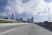 empty highway running over overpasss with highrise buildings in the distance and a blue sky above