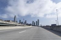 empty highway running over overpasss with highrise buildings in the distance and a blue sky above