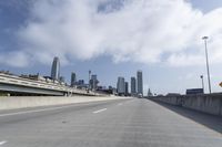 empty highway running over overpasss with highrise buildings in the distance and a blue sky above