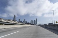 empty highway running over overpasss with highrise buildings in the distance and a blue sky above