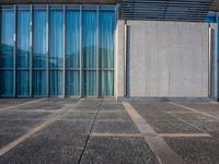 a sidewalk that has several glass doors next to it with buildings in the background behind