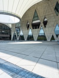 large concrete building with curved glass windowed roof, outside view, and open walkway