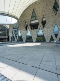 large concrete building with curved glass windowed roof, outside view, and open walkway