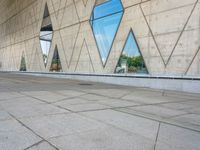 the entrance to an empty building has several large windows reflecting it's surroundings across the street