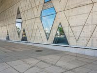 the entrance to an empty building has several large windows reflecting it's surroundings across the street