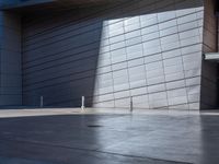 a skateboarder performs a trick in front of a building with metal cladding