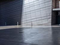 a skateboarder performs a trick in front of a building with metal cladding