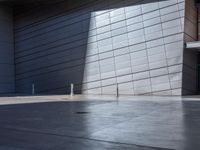 a skateboarder performs a trick in front of a building with metal cladding