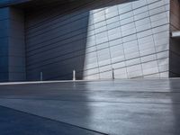 a skateboarder performs a trick in front of a building with metal cladding