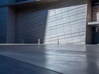 a skateboarder performs a trick in front of a building with metal cladding