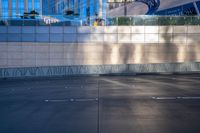 a parking lot in the middle of a city area with buildings reflected on glass wall