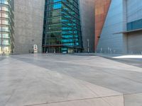 some very tall buildings with lots of windows and silver concrete tiles on the ground of a square concrete floor