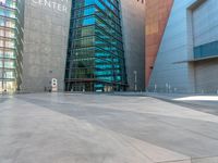 some very tall buildings with lots of windows and silver concrete tiles on the ground of a square concrete floor