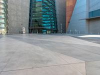 some very tall buildings with lots of windows and silver concrete tiles on the ground of a square concrete floor