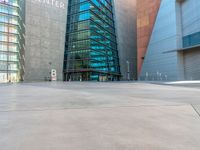 some very tall buildings with lots of windows and silver concrete tiles on the ground of a square concrete floor