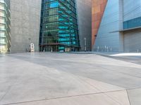 some very tall buildings with lots of windows and silver concrete tiles on the ground of a square concrete floor