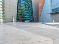 some very tall buildings with lots of windows and silver concrete tiles on the ground of a square concrete floor