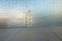 a man rides his skateboard across an outdoor area next to a wall of concrete