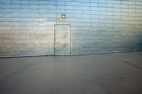 a man rides his skateboard across an outdoor area next to a wall of concrete