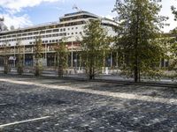 a picture of a large building in the background with people walking around it and some trees