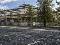 a picture of a large building in the background with people walking around it and some trees