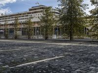 a picture of a large building in the background with people walking around it and some trees