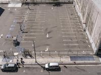 an empty parking lot with no people in it in winter day and two white vans parked nearby