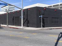 an empty black building on a city street with red lights near a traffic light and crosswalk