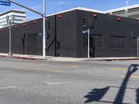 an empty black building on a city street with red lights near a traffic light and crosswalk