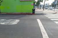 an intersection with signs and advertisements, as well as buildings and trees, near a crosswalk