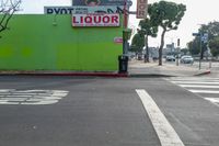 an intersection with signs and advertisements, as well as buildings and trees, near a crosswalk