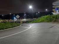 a empty road and several street lights at night time of the day in the middle of a green grassy hill