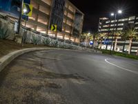 the asphalted road is empty outside the building at night, with parking spaces at the curb