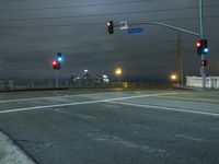 a traffic light sitting next to a road under a dark sky with buildings below it