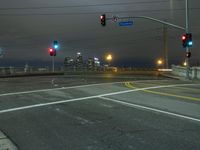 a traffic light sitting next to a road under a dark sky with buildings below it