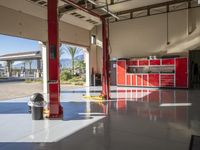 the inside of a car garage with two red cabinets and two chairs in it and a gas pump and fire hydrant