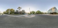 a circle shot of the road that goes through an intersection with trees and buildings around it