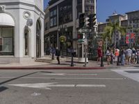 people cross the street in front of a building on a sunny day of the year