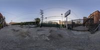 a panoramagraph image of a fence and building in an alleyway near a stair case